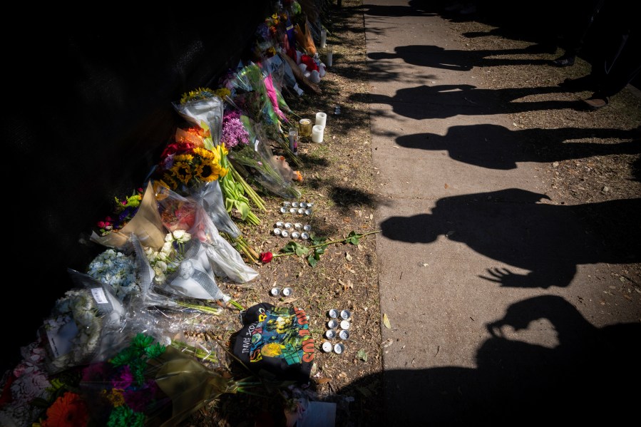 Visitors cast shadows at a memorial to the victims of the Astroworld concert in Houston on Nov. 7, 2021. The 10 people who lost their lives in a massive crowd surge at the Astroworld music festival in Houston died from compression asphyxia, officials announced Thursday, Dec. 16, 2021. (AP Photo/Robert Bumsted, File)