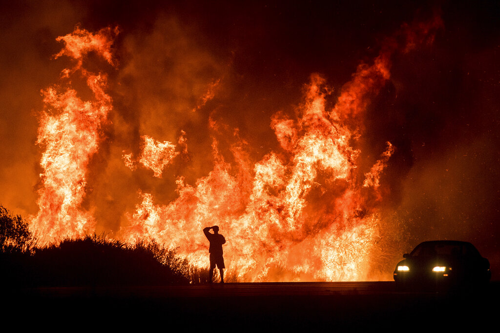 A motorists on Highway 101 watches flames from the Thomas fire leap above the roadway north of Ventura, Calif., on Dec. 6, 2017. (AP Photo/Noah Berger, File)