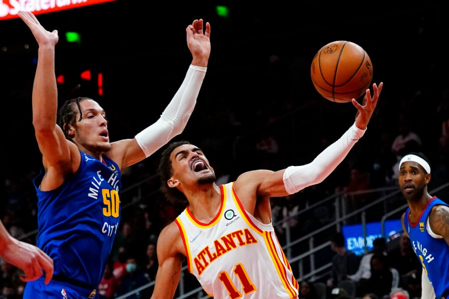 Atlanta Hawks guard Trae Young (11) goes past Denver Nuggets forward Aaron Gordon (50) during the first half of an NBA basketball game Friday, Dec. 17, 2021, in Atlanta. (AP Photo/John Bazemore)