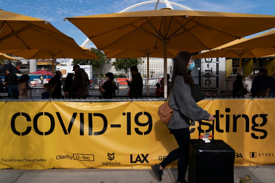 Travelers wait in line to get tested for COVID-19 at Los Angeles International Airport in Los Angeles, Monday, Dec. 20, 2021. (AP Photo/Jae C. Hong)