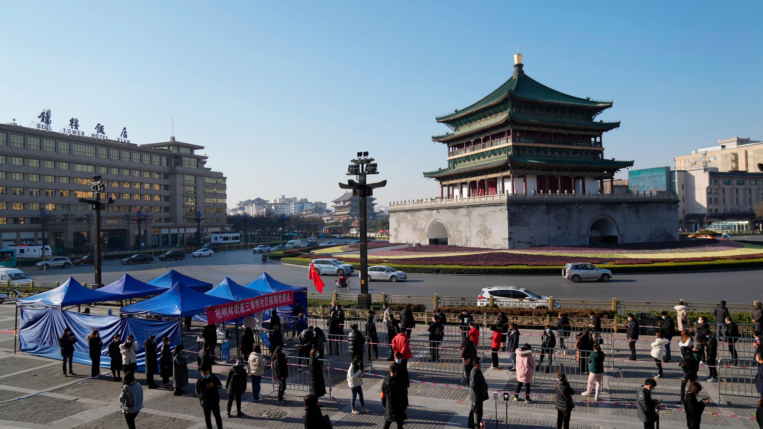 In this photo released by China's Xinhua News Agency, residents line up for tests at a COVID-19 testing site in Xi'an in northwestern China's Shaanxi Province, Tuesday, Dec. 21, 2021. China on Wednesday ordered millions of people locked down in neighborhoods and workplaces in the northern city of Xi'an following a spike in coronavirus cases. (Li Yibo/Xinhua via AP)