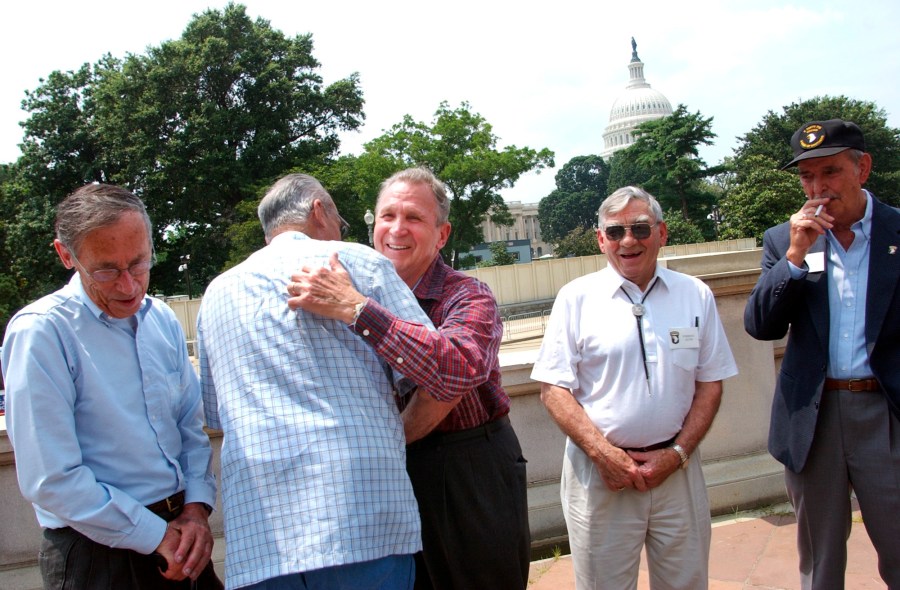 Edward Shames, center, hugs Ed McClung, center left, both members of the World War II Army Company E of the 506th Regiment of the 101st Airborne, with veterans Jack Foley, left, Joe Lesniewski, right, and Shifty Powers, far right, at the Library of Congress in Washington, on July 16, 2003. Shames, who was the last surviving officer of “Easy Company,” which inspired the HBO miniseries and book “Band of Brothers,” has died at age 99. An obituary posted by the Holomon-Brown Funeral Home & Crematory said Shames, of Norfolk, Va., died peacefully at his home on Friday, Dec. 3, 2021. (AP Photo/Gerald Herbert, File)