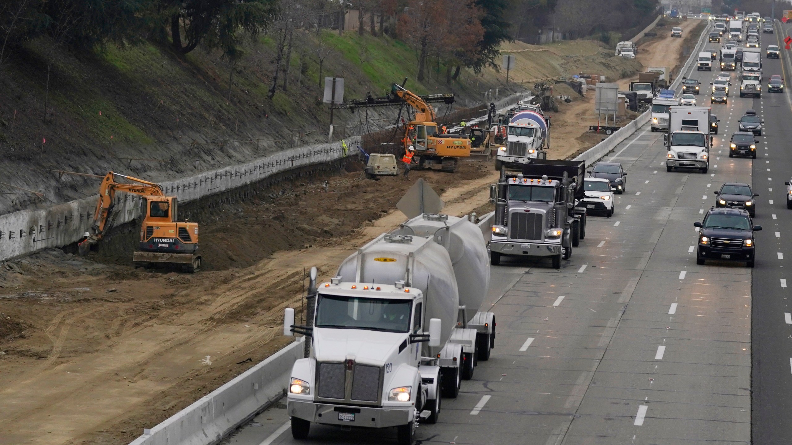 Trucks and other vehicles pass a construction zone on Highway 50 in Sacramento, Calif., Monday, Dec. 6, 2021. The California Air Resources Board, on Thursday, Dec. 9, 2021, is considering a new smog check program for heavy duty trucks. The new rules would require trucks weighing more than 14,000 pounds to be tested at least twice per year to make sure they meet the state's smog standards. (AP Photo/Rich Pedroncelli)