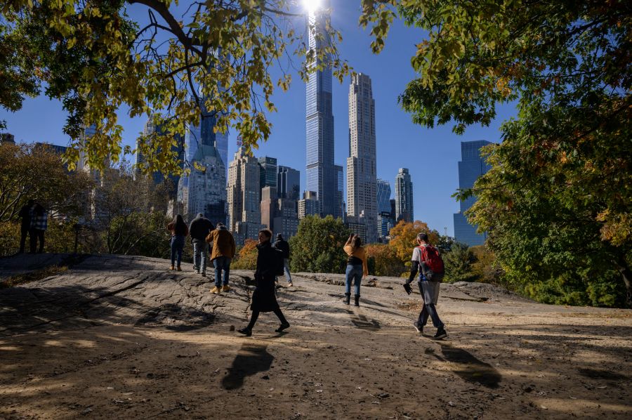 People stand beneath fall foliage and before high-rise buildings of the Manhattan city skyline in Central Park in New York on Nov. 5, 2021. (ED JONES/AFP via Getty Images)