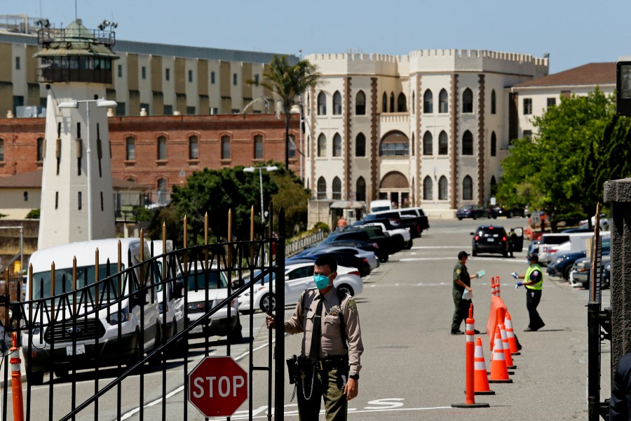 In this July 9, 2020, file photo, a correctional officer closes the main gate at San Quentin State Prison in San Quentin, Calif. With a new and more infectious coronavirus variant sweeping California, attorneys representing inmates say violations of health orders by prison staff risk a repeat of the outbreaks that killed dozens in the first year of the pandemic. Gov. Gavin Newsom's administration is fighting a federal judge's order that all California prison workers must be vaccinated against the coronavirus or have a religious or medical exemption. (AP Photo/Eric Risberg, File)