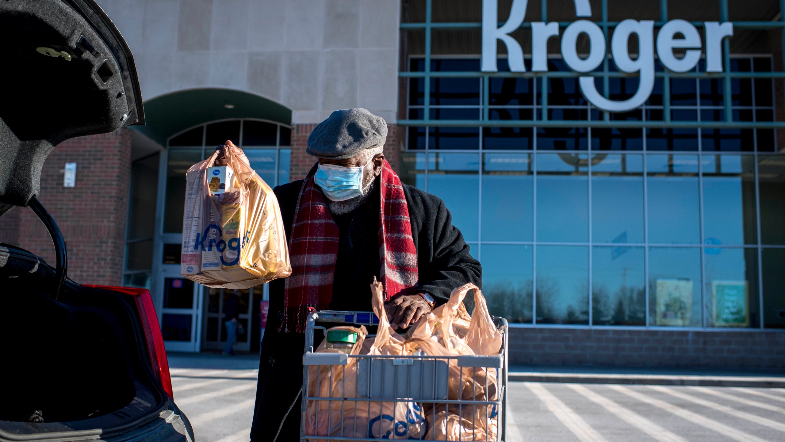 A shopper loads his car with groceries at the Kroger in Novi, Mich on Jan. 23, 2021. Kroger says, Tuesday, Dec. 14, it is modifying some of its COVID-19 policies. Unvaccinated workers will no longer receive certain COVID-19 leave benefits if they get the virus, and some who refuse the shot will also have to pay a monthly health insurance surcharge. (Nic Antaya/Detroit News via AP)