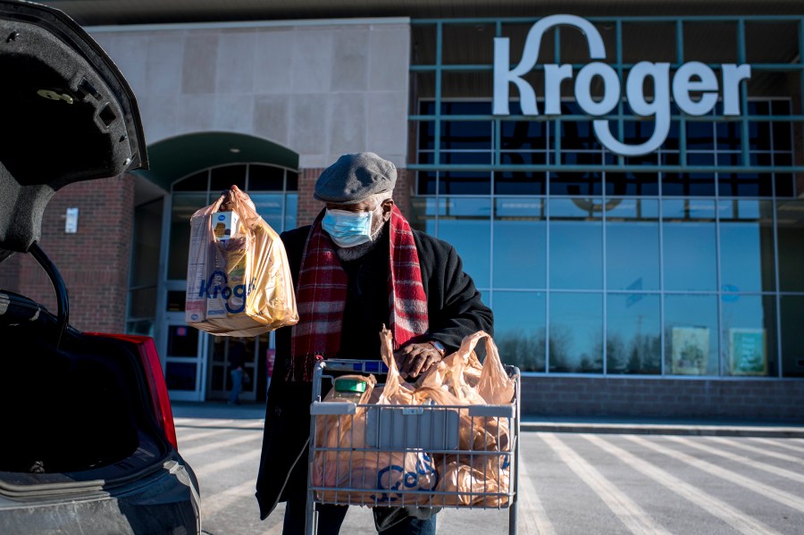 A shopper loads his car with groceries at the Kroger in Novi, Mich on Jan. 23, 2021. Kroger says, Tuesday, Dec. 14, it is modifying some of its COVID-19 policies. Unvaccinated workers will no longer receive certain COVID-19 leave benefits if they get the virus, and some who refuse the shot will also have to pay a monthly health insurance surcharge. (Nic Antaya/Detroit News via AP)