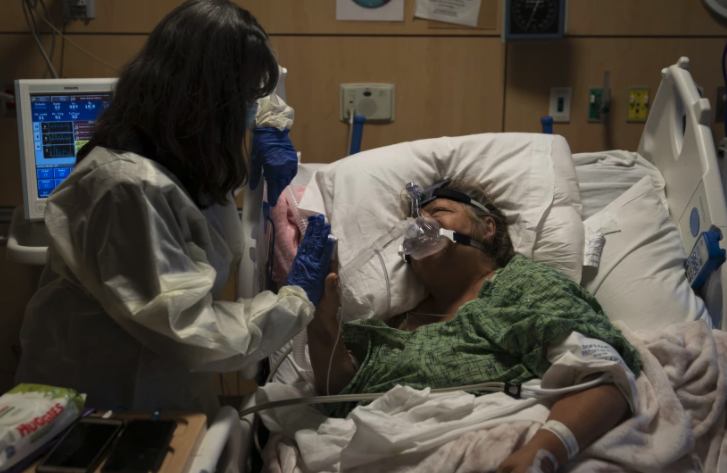 Becky Gonzalez, left, visits longtime friend Mary Lou Samora, a 71-year-old COVID-19 patient, at Providence Holy Cross Medical Center in Los Angeles on Friday.(Jae C. Hong / Associated Press)