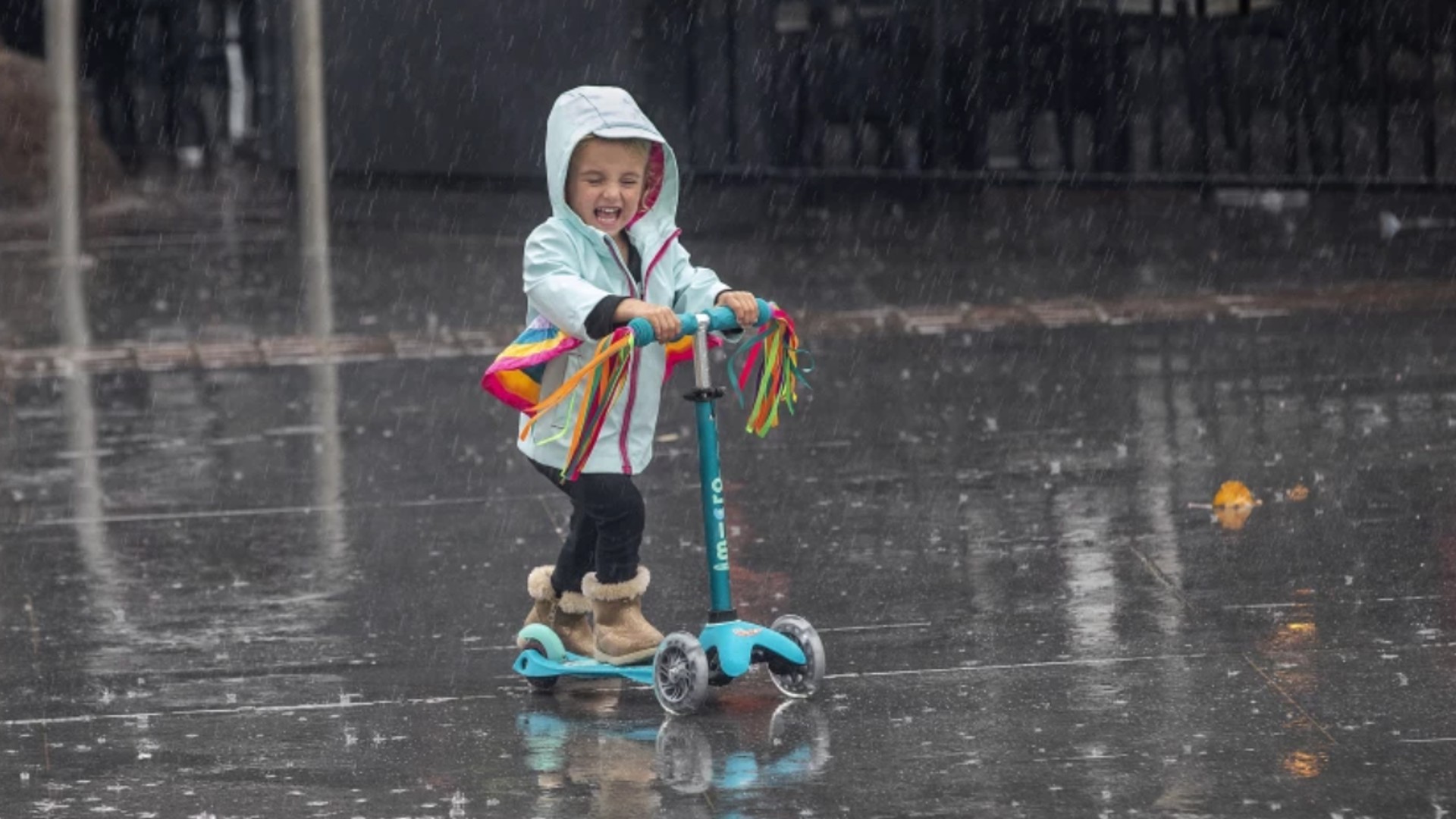 Addison McConnell, 2, of Redondo Beach rides her scooter in the rain during a family outing in Hermosa Beach.(Mel Melcon / Los Angeles Times)