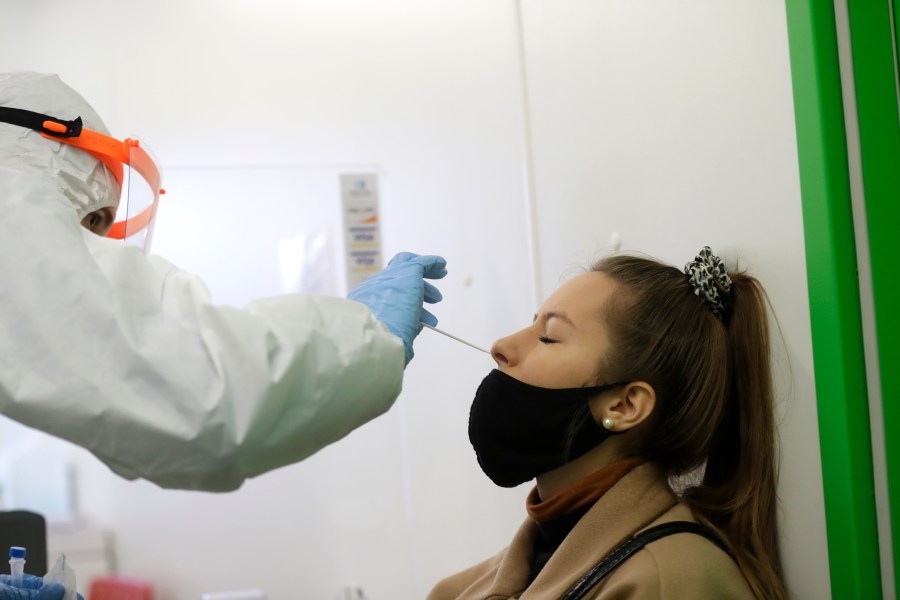 A woman undergoes the rapid antigen test for the coronavirus in Prague, Czech Republic, Wednesday, Dec. 16, 2020. On Wednesday Jan. 5, 2022 the Czech Republic's government decided to cut quarantine restrictions from fourteen to five days while also similarly shortened time for close contacts of infected people to isolate. (AP Photo/Petr David Josek, file)