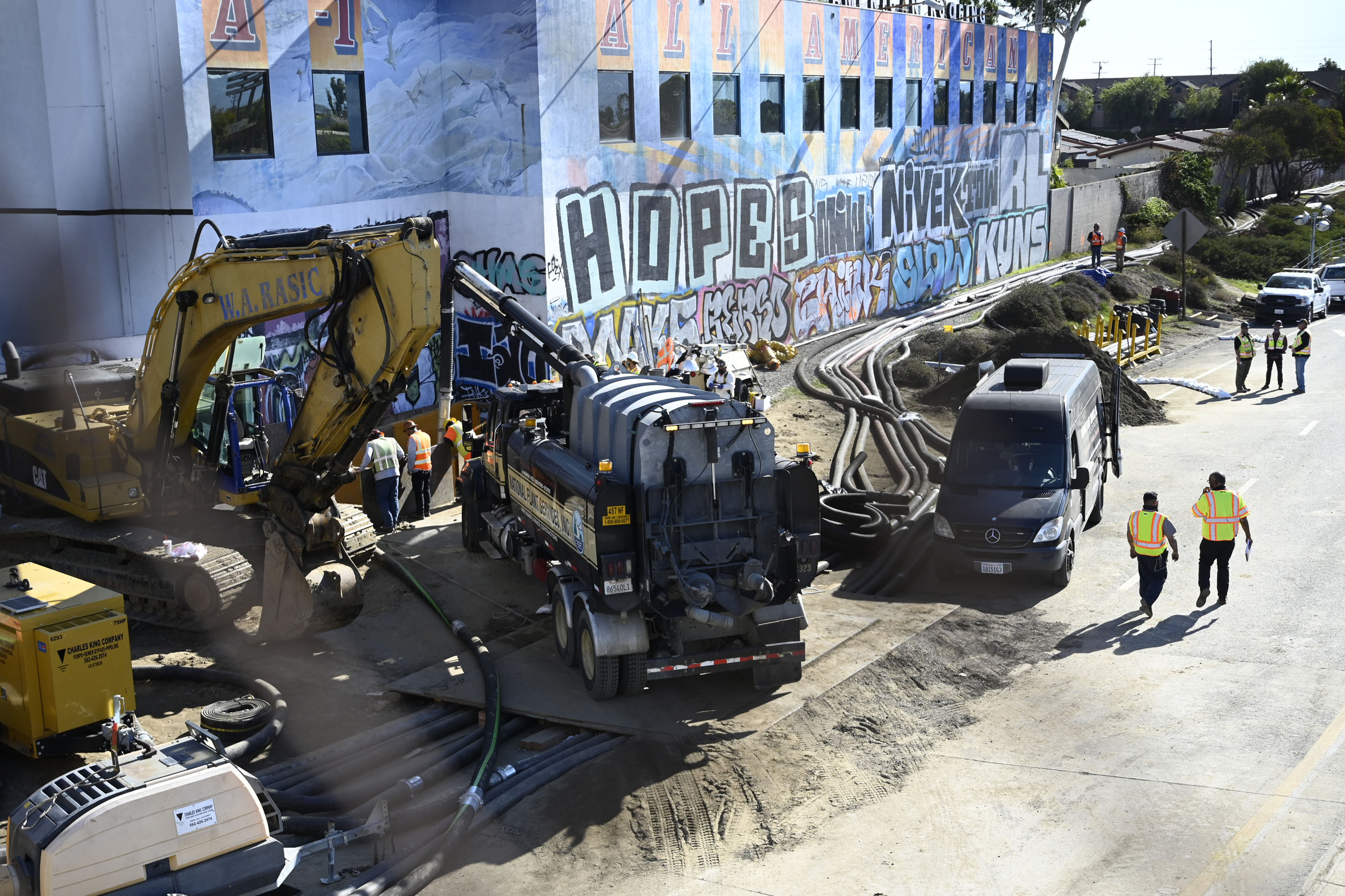 Crews work on the pipe break that caused a sewage spill this past week in Carson, Calif., on Jan. 3, 2022. Temporary pipes are detouring the sewage about 1,000 feet while repairs are made on the line. (Brittany Murray/The Orange County Register via AP)