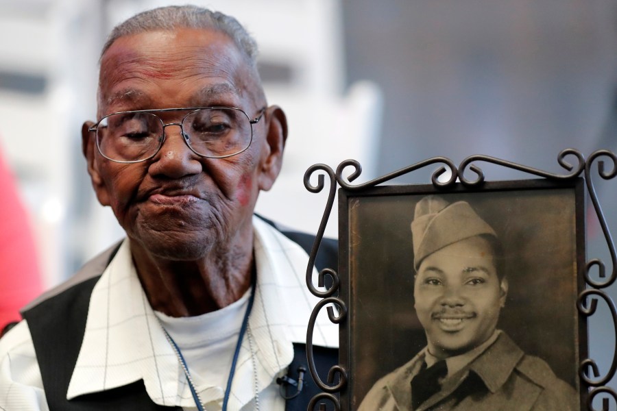 World War II veteran Lawrence Brooks holds a photo of him taken in 1943, as he celebrates his 110th birthday at the National World War II Museum in New Orleans, on Sept. 12, 2019. Brooks, the oldest World War II veteran in the U.S. — and believed to be the oldest man in the country — died on Wednesday, Jan. 5, ,2022 at the age of 112. (AP Photo/Gerald Herbert, File)