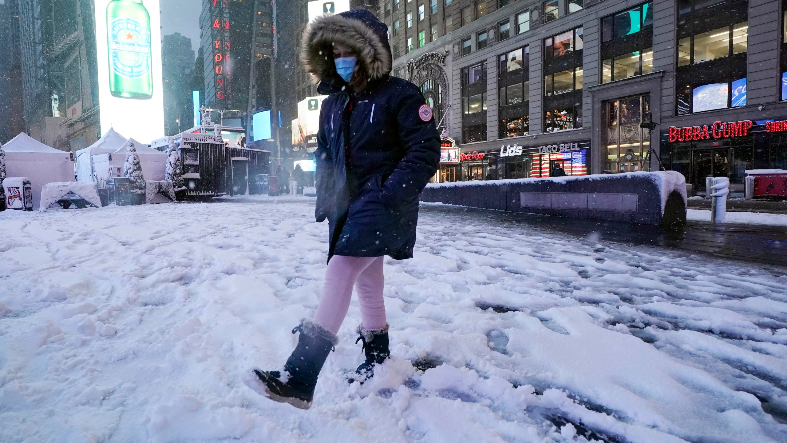 A girl kicks at snow in New York's Times Square on Jan. 7, 2022. A winter storm that has already left areas of the south with more than 6 inches of snow moved into the northeast during the morning commute and prompted many school districts to close for the day. (AP Photo/Richard Drew)