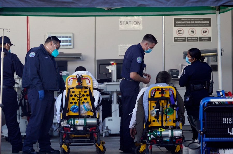 Los Angeles County emergency medical technicians deliver patients for admission at the Ambulatory Care Center station at the MLK Community Medical Group hospital in Los Angeles, Wednesday, Feb. 24, 2021. (AP Photo/Damian Dovarganes, File)