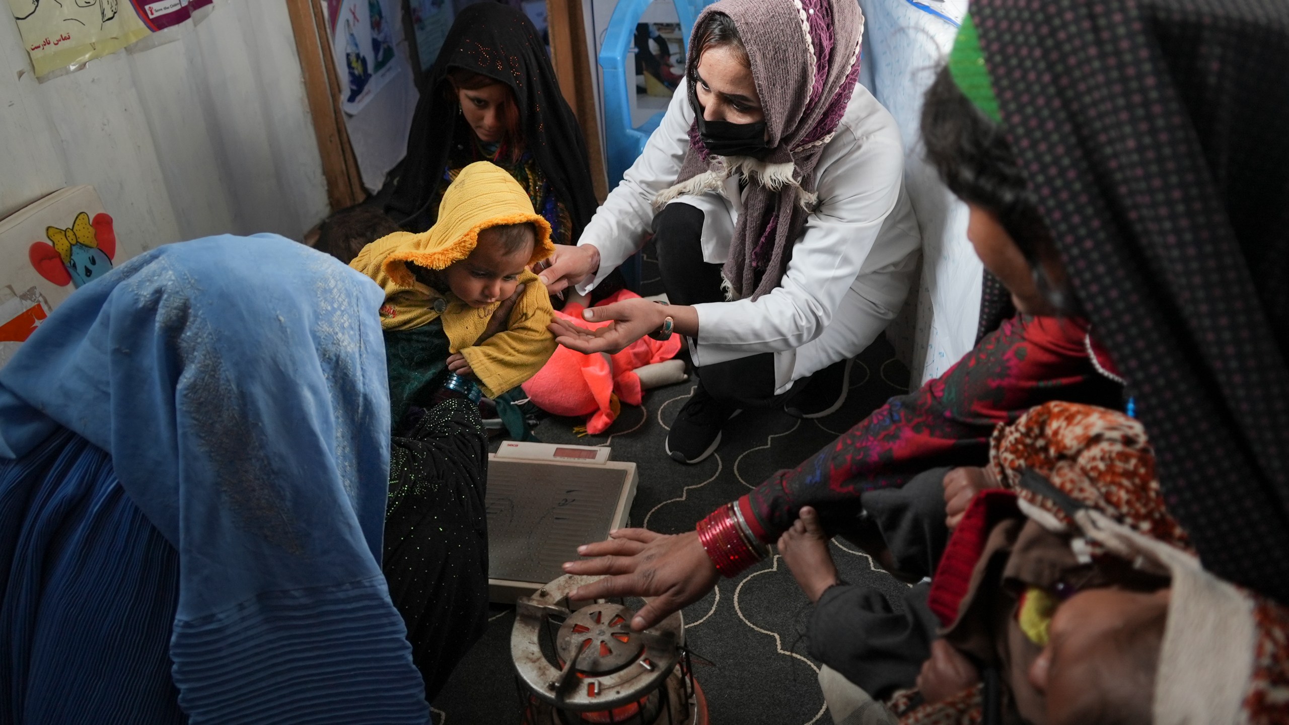 A nurse checks the weight of a child in a makeshift clinic organized by World Vision at a settlement near Herat, Afghanistan, Dec. 16, 2021. In a statement Tuesday, Jan. 11, 2022, the White House announced $308 million in additional humanitarian assistance for Afghanistan, offering new aid to the country as it edges toward a humanitarian crisis since the Taliban takeover nearly five months earlier. (AP Photo/Mstyslav Chernov, File)