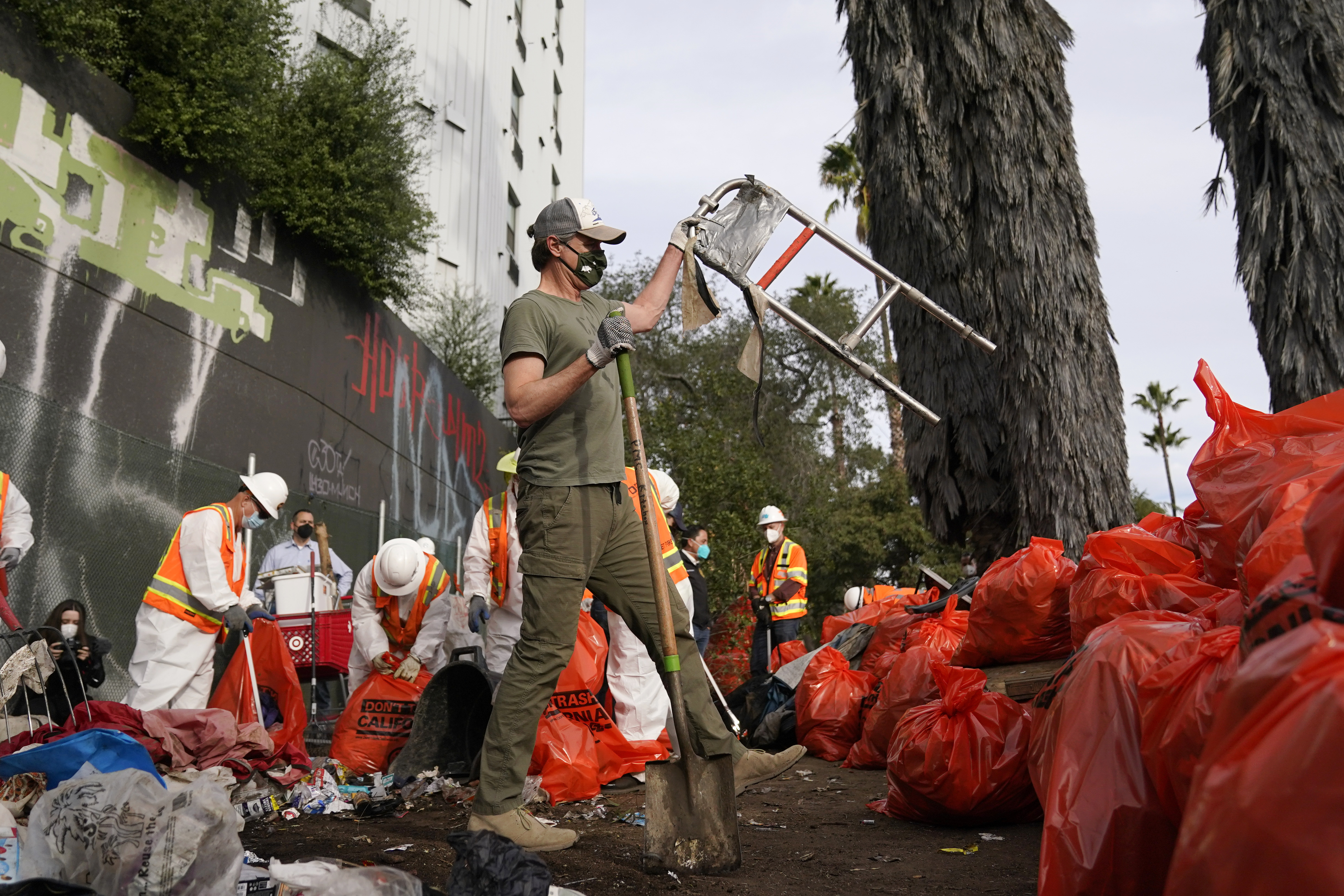 California Gov. Gavin Newsom, center, helps clean a homeless encampment alongside a freeway on Jan. 12, 2022, in San Diego. (AP Photo/Gregory Bull)