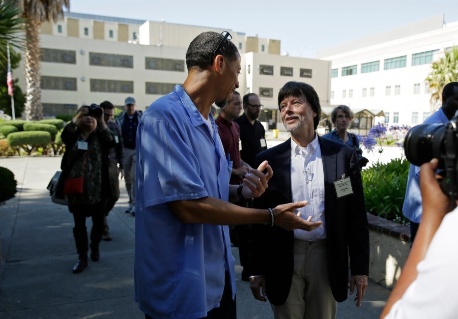 In this July 24, 2019, file photo, filmmaker Ken Burns walks with inmate Rahsaan Thomas at San Quentin State Prison in San Quentin, Calif. Burns visited the prison to show parts of his new documentary, Country Music. (AP Photo/Eric Risberg, File)