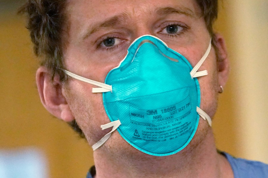 Registered nurse Scott McGieson wears an N95 mask as he walks out of a patient's room in the acute care unit of Harborview Medical Center, Friday, Jan. 14, 2022, in Seattle. Washington Gov. Jay Inslee is deploying 100 members of the state National Guard to hospitals across the state amid staff shortages due to an omicron-fueled spike in COVID-19 hospitalizations. Inslee announced Thursday that teams will be deployed to assist four overcrowded emergency departments at hospitals in Everett, Yakima, Wenatchee and Spokane, and that testing teams will be based at hospitals in Olympia, Richland, Seattle and Tacoma. (AP Photo/Elaine Thompson)