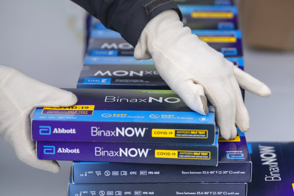 Youngstown City Health Department worker Faith Terreri grabs two at-home COVID-19 test kits to be handed out during a distribution event. (AP Photo/David Dermer, File)