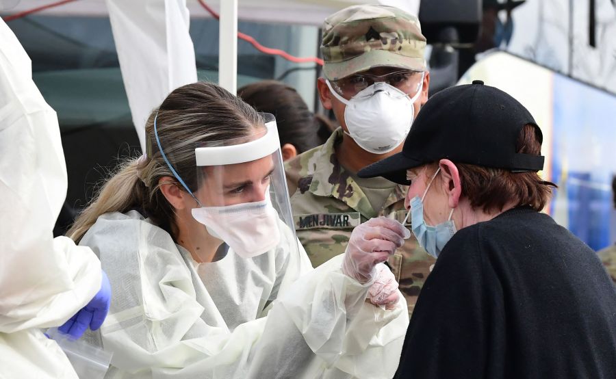 A woman receives help with a nasal swab at a BusTest Express Covid-19 mobile testing site in Paramount, a city in Los Angeles County on Jan. 12, 2022. (FREDERIC J. BROWN/AFP via Getty Images)