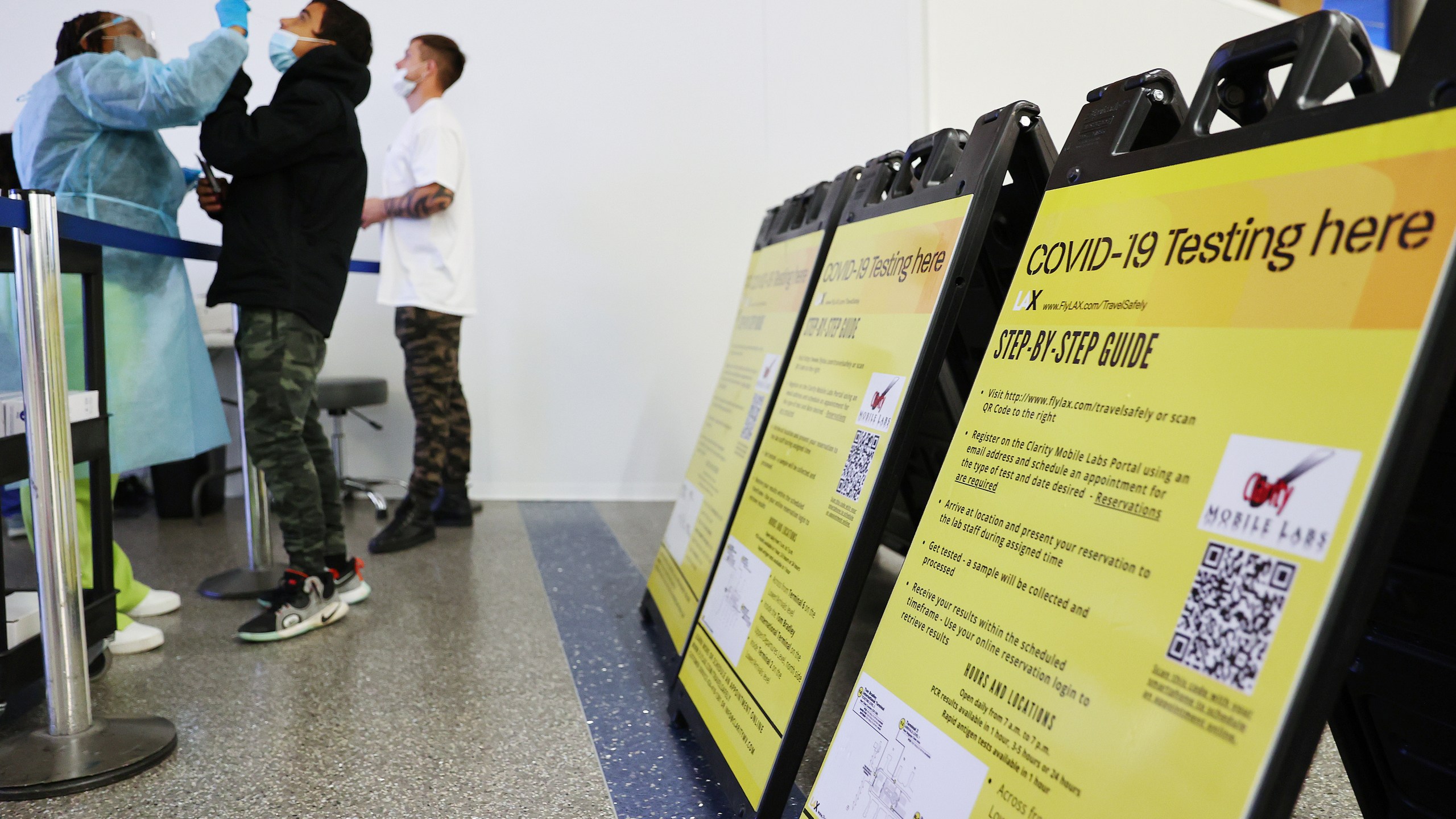 Merline Jimenez (L) administers a COVID-19 nasopharyngeal swab to a person at a testing site located in the international terminal at Los Angeles International Airport amid a surge in omicron variant cases on Dec. 21, 2021. (Mario Tama/Getty Images)