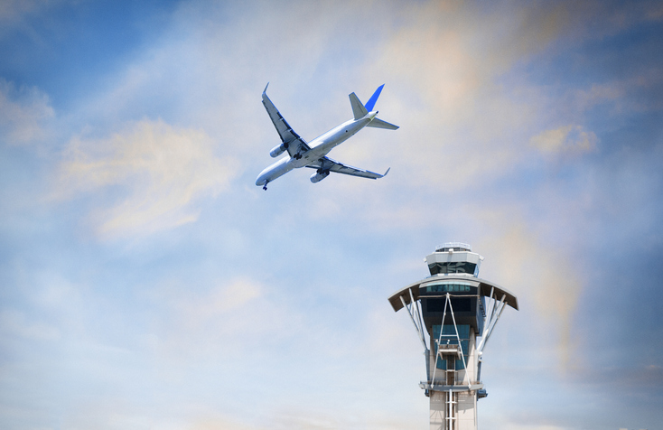 An airplane flying over air traffic control tower at LAX in California. (Getty Images)