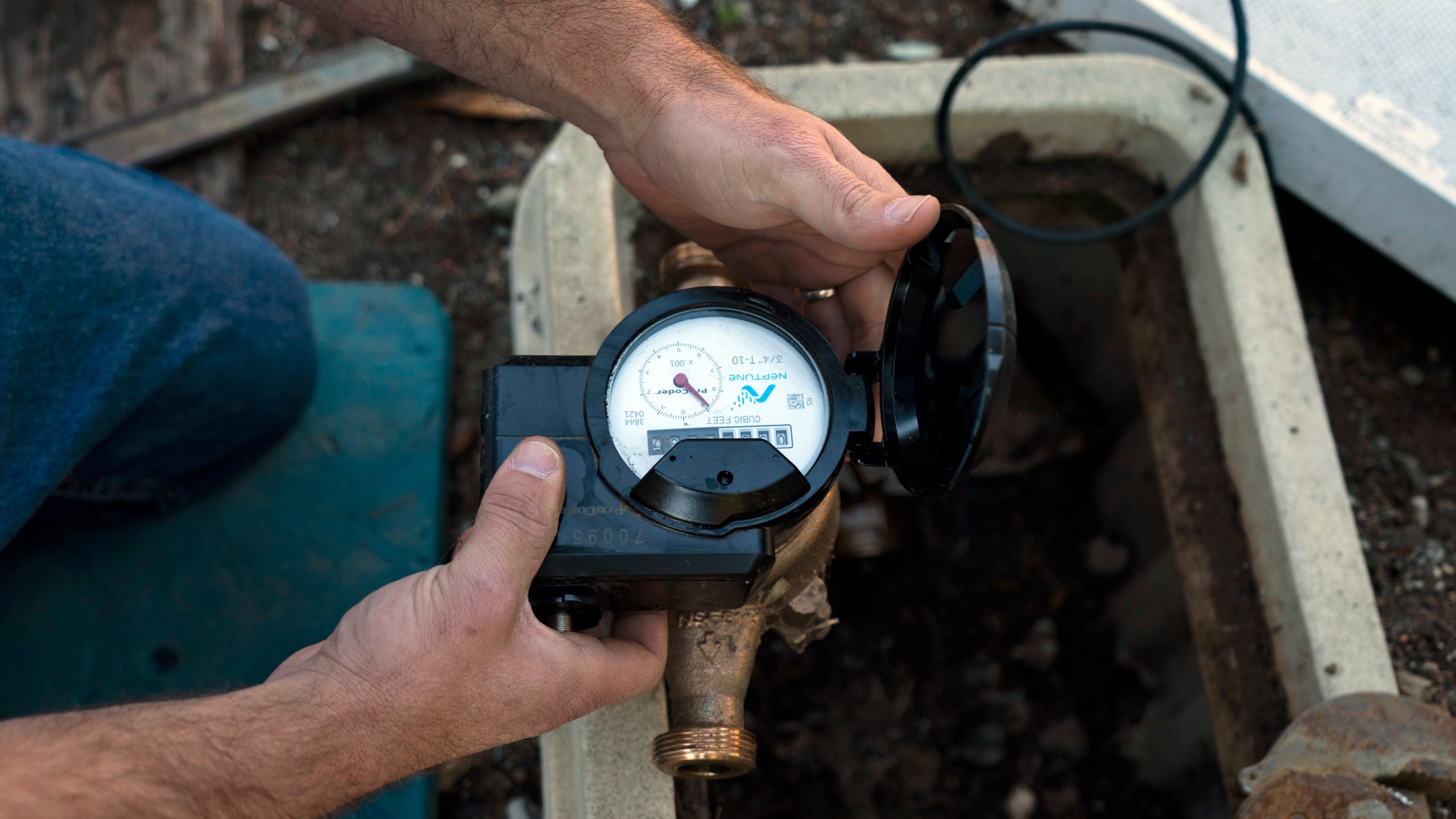 Cason Gilmer, a senior field customer service representative from the Las Virgenes Municipal Water District, installs an advanced water metering system in Agora Hills , Calif., Wednesday, Jan. 5, 2022. The wealthy enclave along the Santa Monica Mountains that is haven for celebrities has taken aggressive steps to try to limit water use during California's drought, including lowering the thresholds for fines for those who go over their "water budgets" and threatening to add restrictors to pipes that limit water flow to customers who repeatedly fail to conserve. (AP Photo/Jae C. Hong)