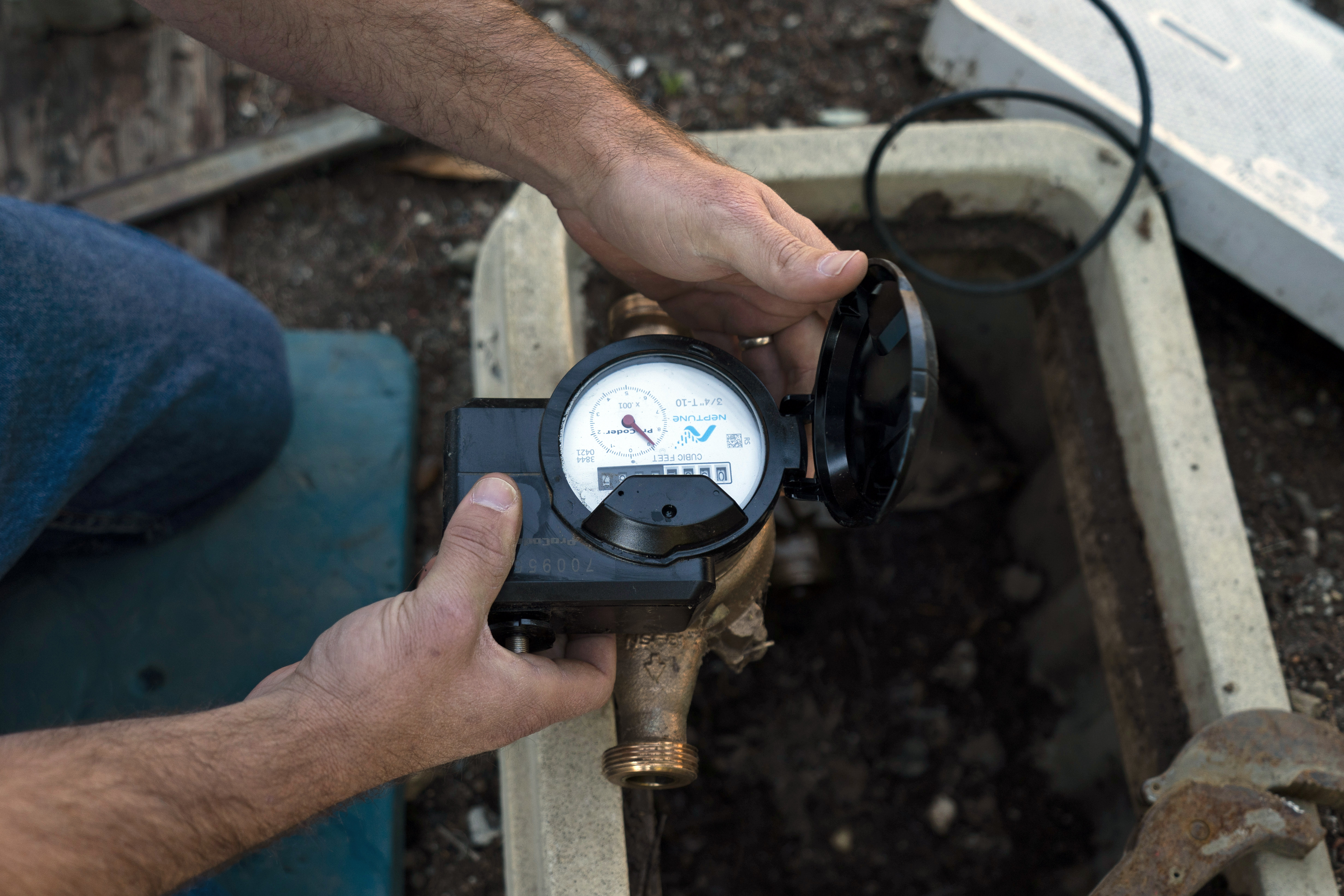 Cason Gilmer, a senior field customer service representative from the Las Virgenes Municipal Water District, installs an advanced water metering system in Agora Hills , Calif., Wednesday, Jan. 5, 2022. The wealthy enclave along the Santa Monica Mountains that is haven for celebrities has taken aggressive steps to try to limit water use during California's drought, including lowering the thresholds for fines for those who go over their "water budgets" and threatening to add restrictors to pipes that limit water flow to customers who repeatedly fail to conserve. (AP Photo/Jae C. Hong)