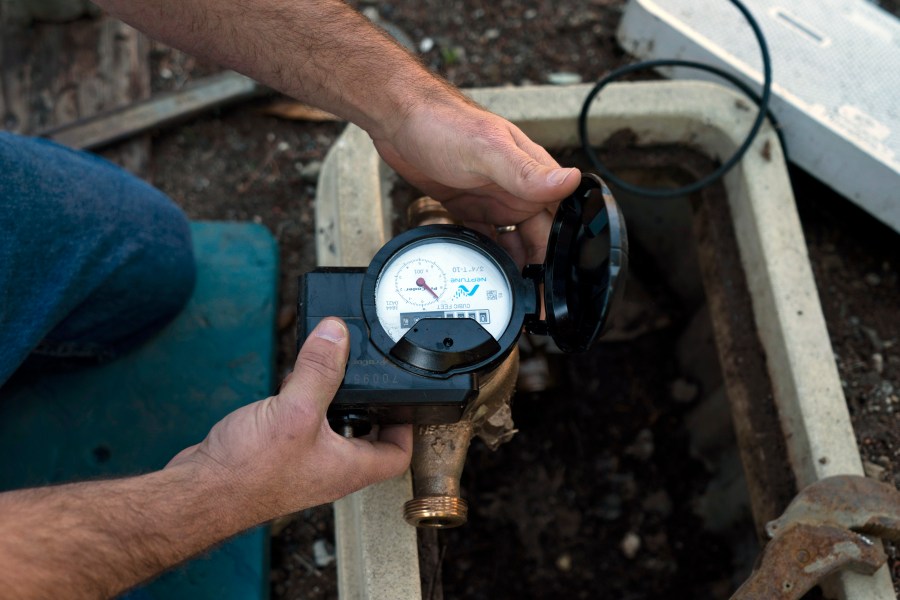 Cason Gilmer, a senior field customer service representative from the Las Virgenes Municipal Water District, installs an advanced water metering system in Agora Hills , Calif., Wednesday, Jan. 5, 2022. The wealthy enclave along the Santa Monica Mountains that is haven for celebrities has taken aggressive steps to try to limit water use during California's drought, including lowering the thresholds for fines for those who go over their "water budgets" and threatening to add restrictors to pipes that limit water flow to customers who repeatedly fail to conserve. (AP Photo/Jae C. Hong)