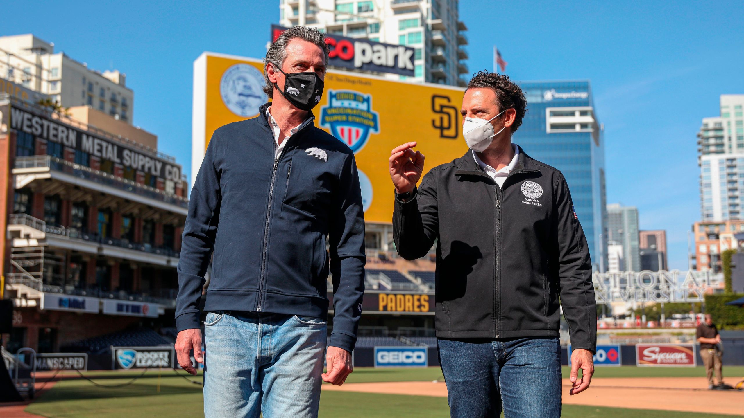 California Gov. Gavin Newsom, left, speaks with Supervisor Nathan Fletcher after a press conference at Petco Park, February 8, 2021 in San Diego, California, during a visit to the Petco Park Vaccination Supersite. (Sandy Huffaker/POOL/AFP)