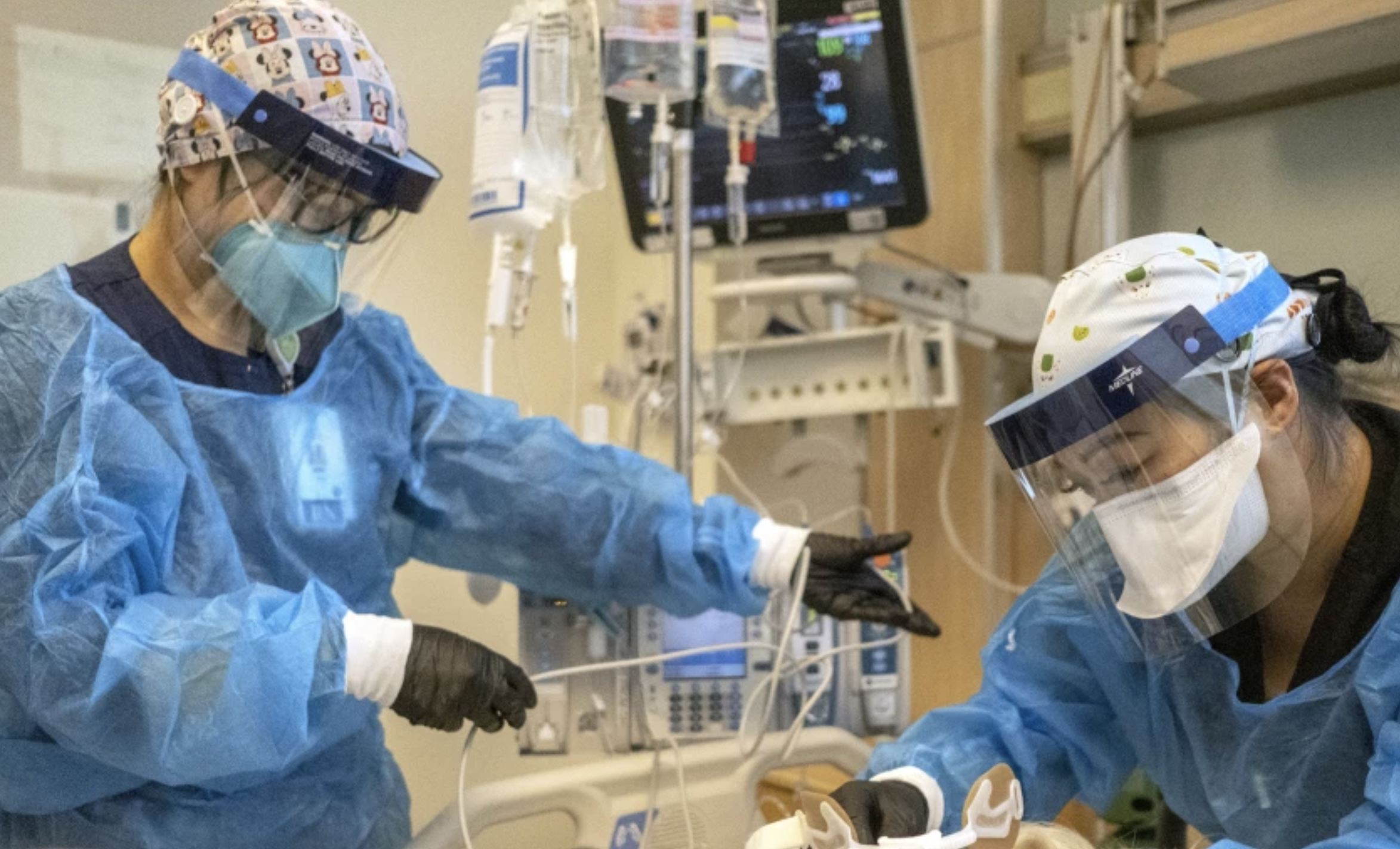 Registered nurse Akiko Gordon, left, and respiratory therapist Janssen Redondo tend to a COVID-19 patient inside the ICU at Martin Luther King Jr. Community Hospital in Los Angeles on Friday.(Francine Orr / Los Angeles Times)