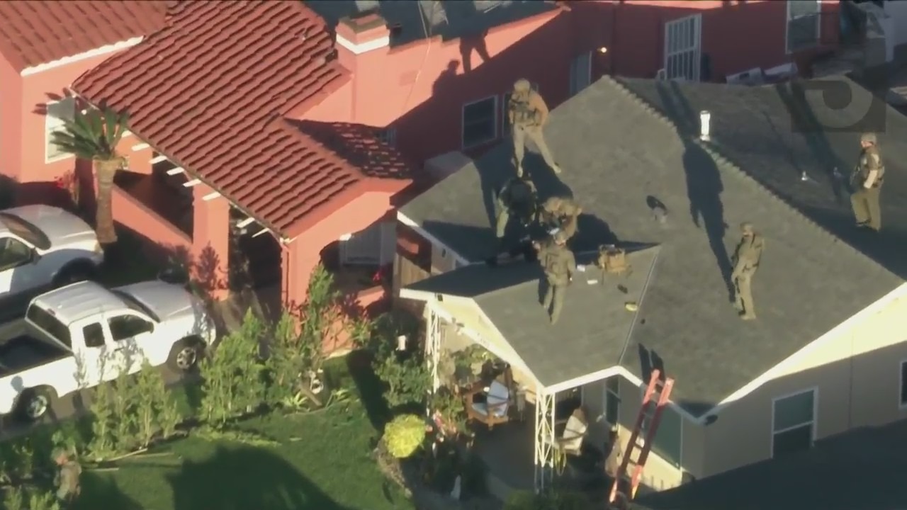 Deputies surround a man is on the roof of a home in the Walnut Park area on Jan. 24, 2022. (KTLA)