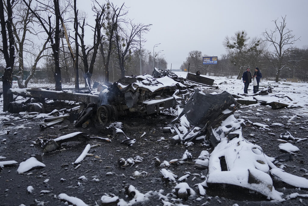 People walk by smoldering destroyed Russian military vehicles on the outskirts of Kharkiv, Ukraine, Friday, Feb. 25, 2022. Russian troops bore down on Ukraine's capital Friday, with gunfire and explosions resonating ever closer to the government quarter, in an invasion of a democratic country that has fueled fears of wider war in Europe and triggered worldwide efforts to make Russia stop. (AP Photo/Vadim Ghirda)