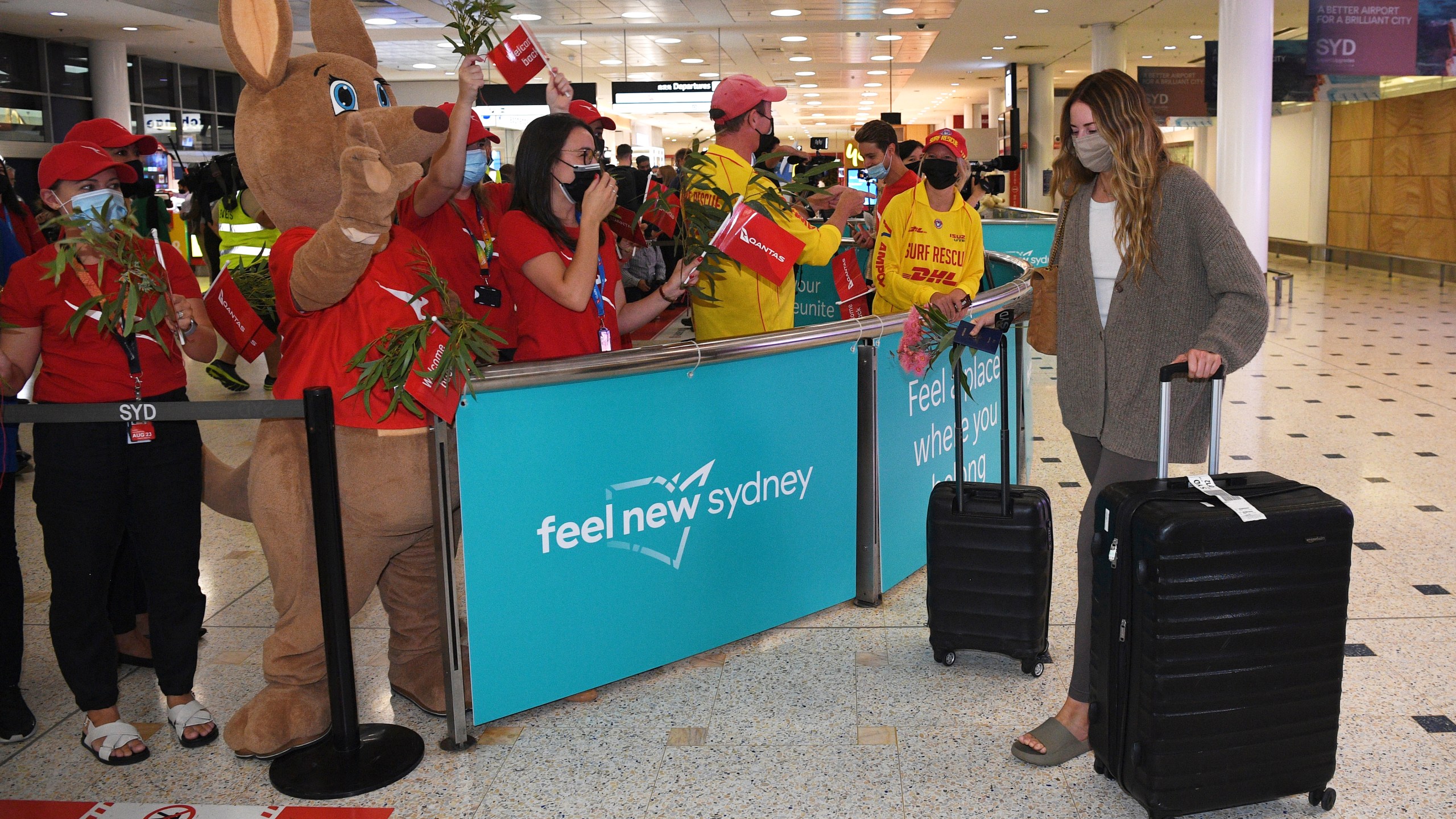 Passengers are welcomed as they arrive at Sydney International Airport in Sydney, Monday, Feb. 21, 2022. International tourists and business travelers began arriving in Australia with few restrictions for the first time in almost two years after the government lifted some of the most draconian pandemic measures of any democracy in the world. (Dean Lewins/AAP Image via AP)