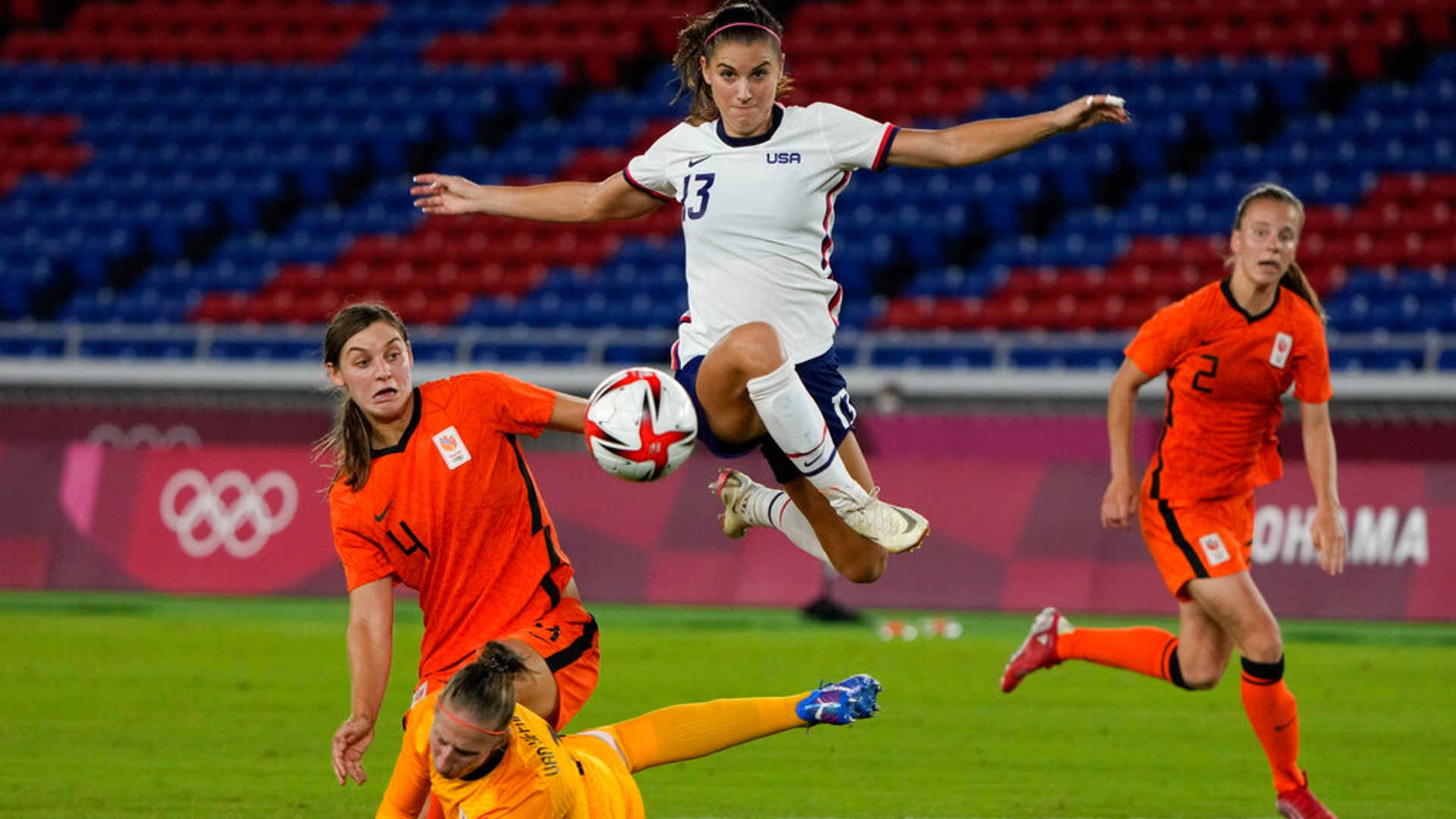 United States' Alex Morgan jumps over Netherlands' goalkeeper Sari van Veenendaal as she attempts to score during a women's quarterfinal soccer match at the 2020 Summer Olympics, Friday, July 30, 2021, in Yokohama, Japan. (AP Photo/Kiichiro Sato, File)