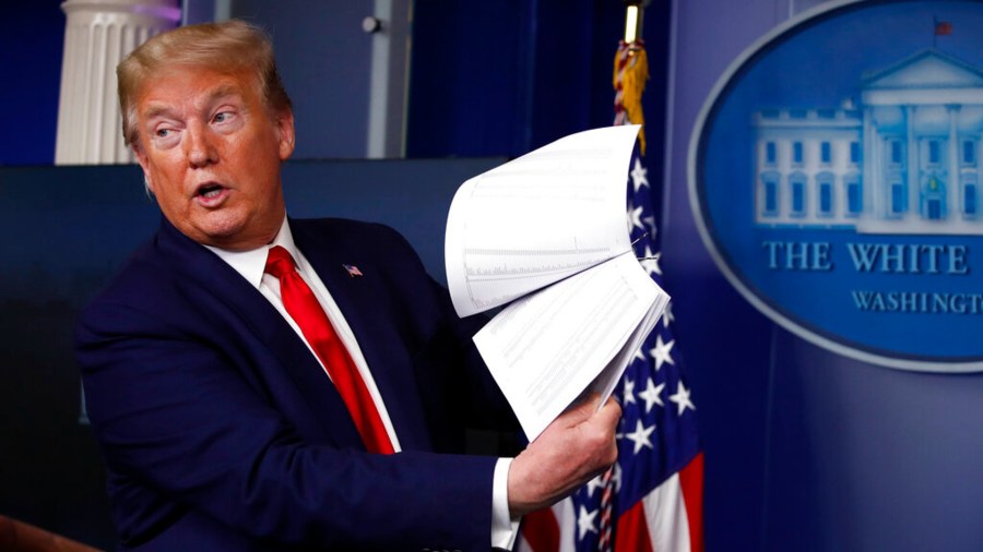 President Donald Trump holds up papers as he speaks about the coronavirus in the James Brady Press Briefing Room of the White House on April 20, 2020, in Washington. (AP Photo/Alex Brandon, File)