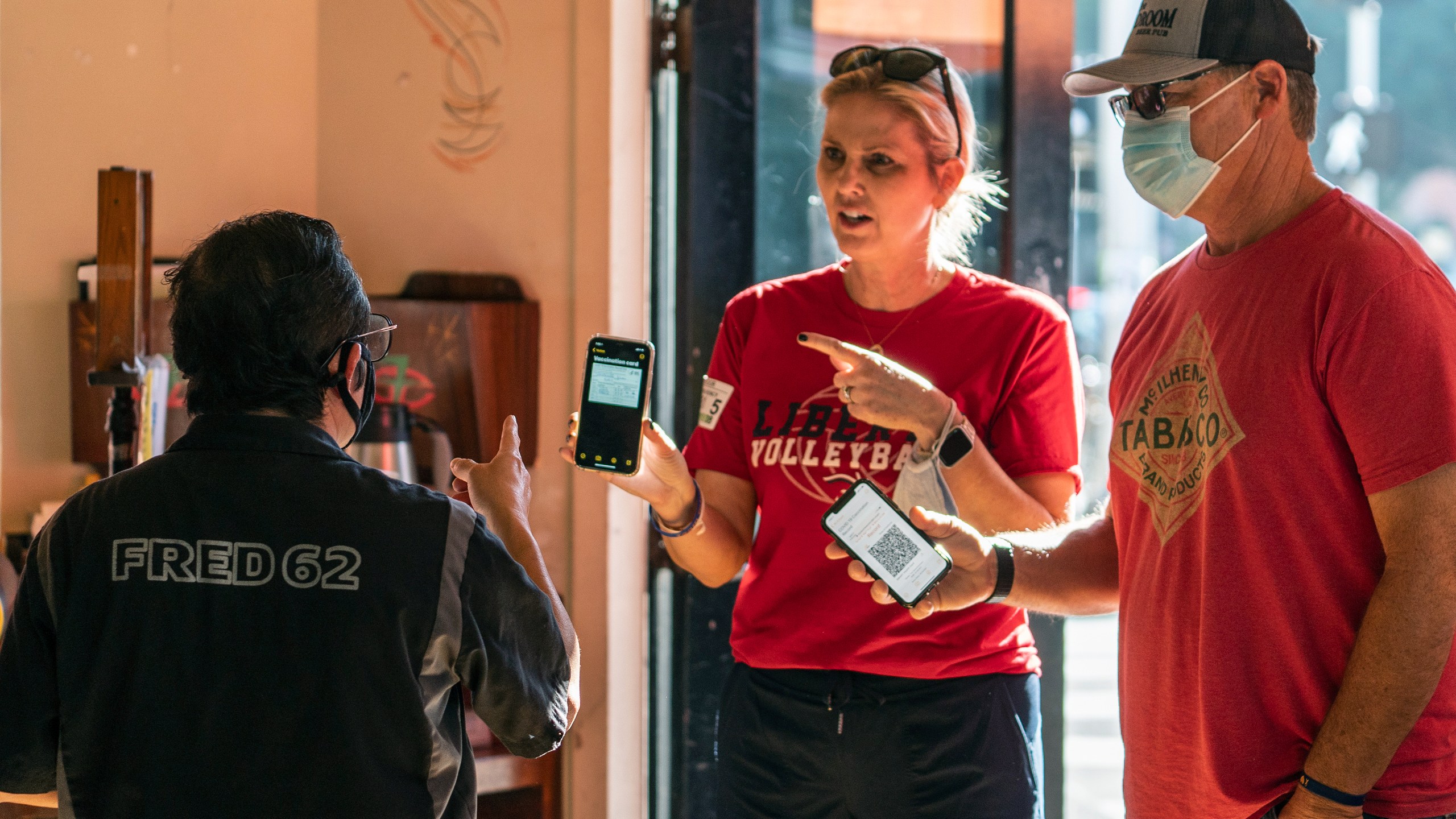 Patrons Naomi and Troy DeMontmorency show their digital vaccination certificates before being allowed to enter the Fred 62 restaurant in the Los Feliz neighborhood of Los Angeles, Nov. 29, 2021. (AP Photo/Damian Dovarganes)