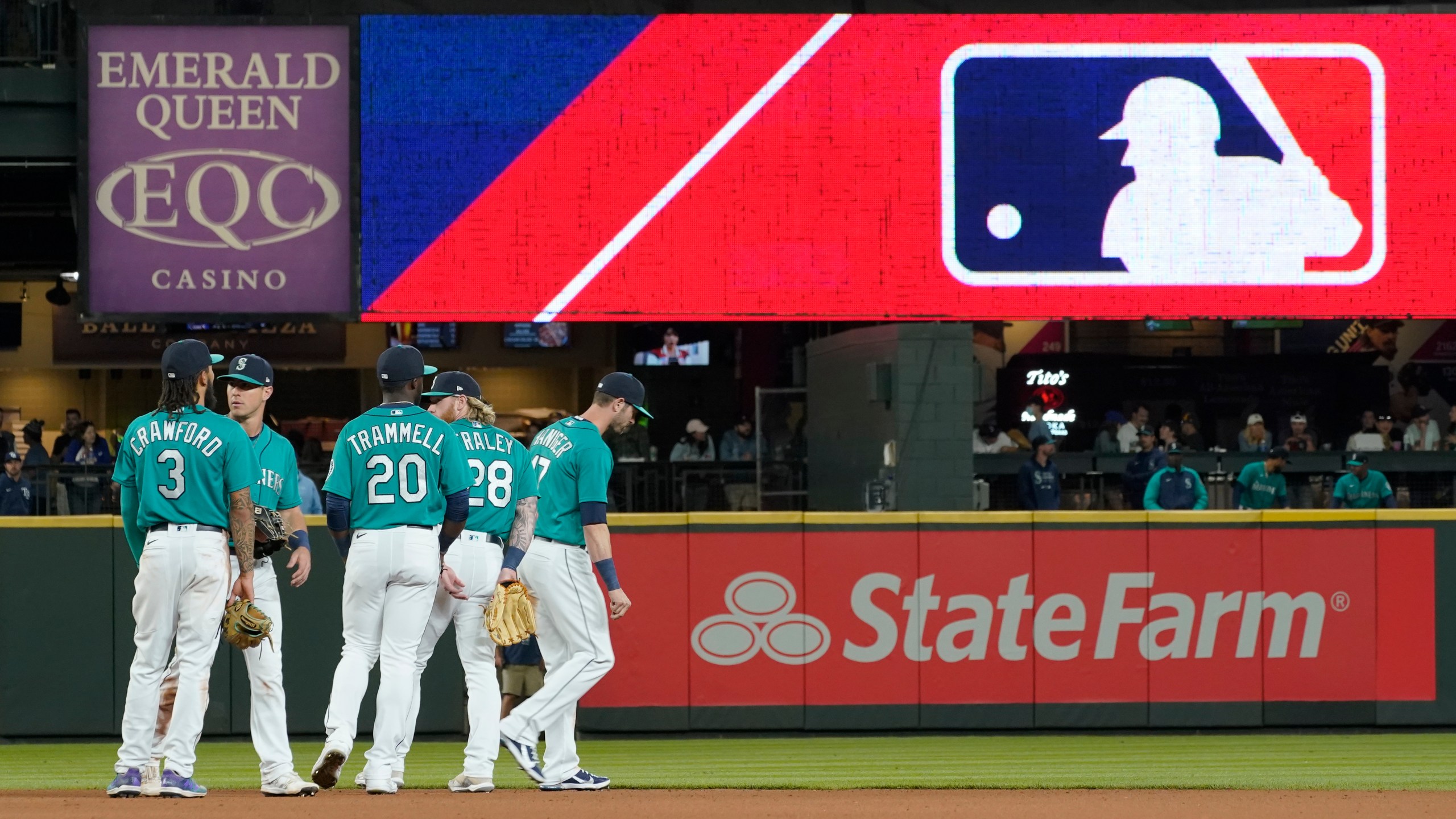 Seattle Mariners gather as the MLB logo is shown during a review of an attempted catch by right fielder Mitch Haniger of a ball hit by Tampa Bay Rays' Ji-Man Choi that was originally called an out during the ninth inning of a baseball game on June 18, 2021 in Seattle. (Ted S. Warren/Associated Press)