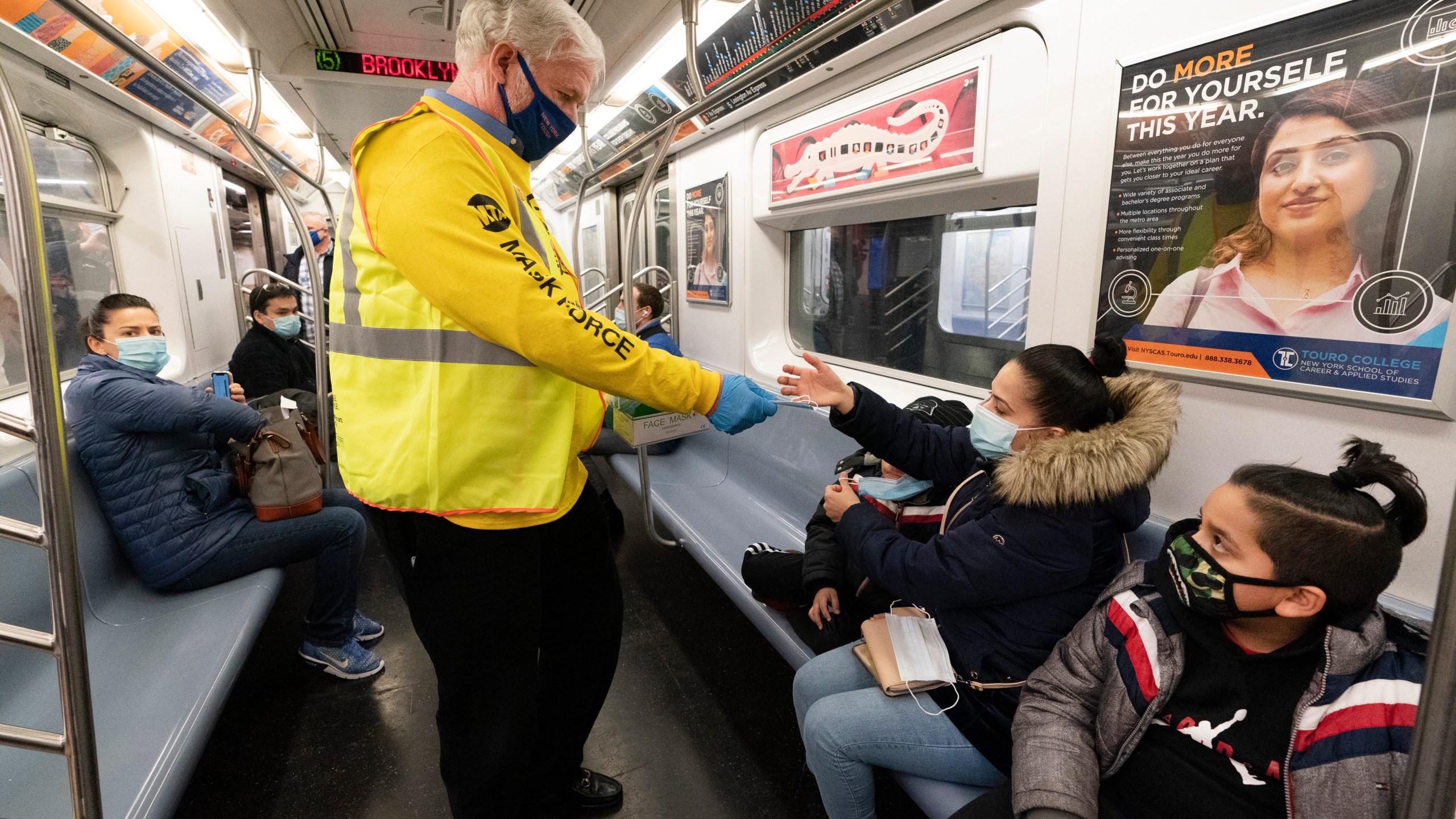 Patrick Foye, Chairman and CEO of the Metropolitan Transportation Authority, hands out face masks on a New York City subway, , Nov. 17, 2020, in New York. The Centers for Disease Control and Prevention is developing guidance that will ease the nationwide mask mandate for public transit next month. That's according to a U.S. official. (AP Photo/Mark Lennihan, File)