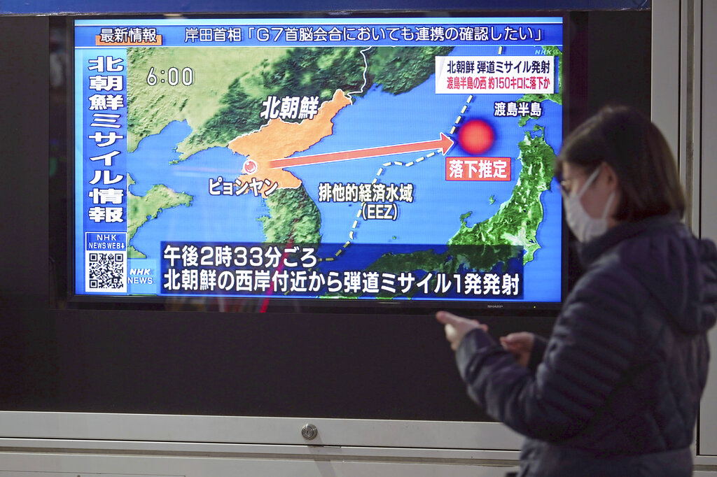 A woman walks along a sidewalk past a TV displaying a news program on North Korea's missile launch Thursday, March 24, 2022, in Tokyo. (AP Photo/Eugene Hoshiko)