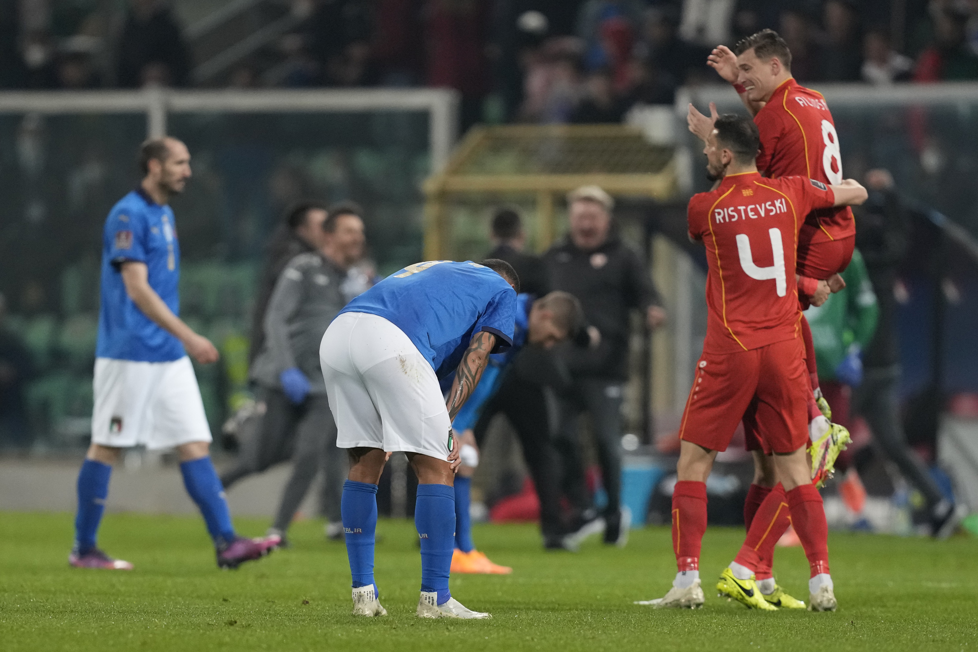 North Macedonia players celebrate as Italy players reacts after their team's elimination at the end of the World Cup qualifying play-off soccer match between Italy and North Macedonia, at Renzo Barbera stadium, in Palermo, Italy on March 24, 2022. North Macedonia won 1-0. (AP Photo/Antonio Calanni)