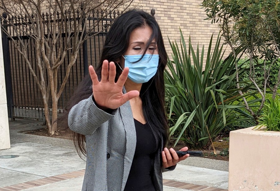 Julie Lee Choi waves off reporters outside Santa Clara Superior Court in San Jose, Calif., on Tuesday, March 29, 2022. Choi, accused of harassing Apple CEO Tim Cook with pleas for sex and other crude suggestions before showing up at his Silicon Valley home last autumn and suggesting she could become violent agreed to stay way from him for the next three years under an agreement approved Tuesday. (AP Photo/Michael Liedtke)