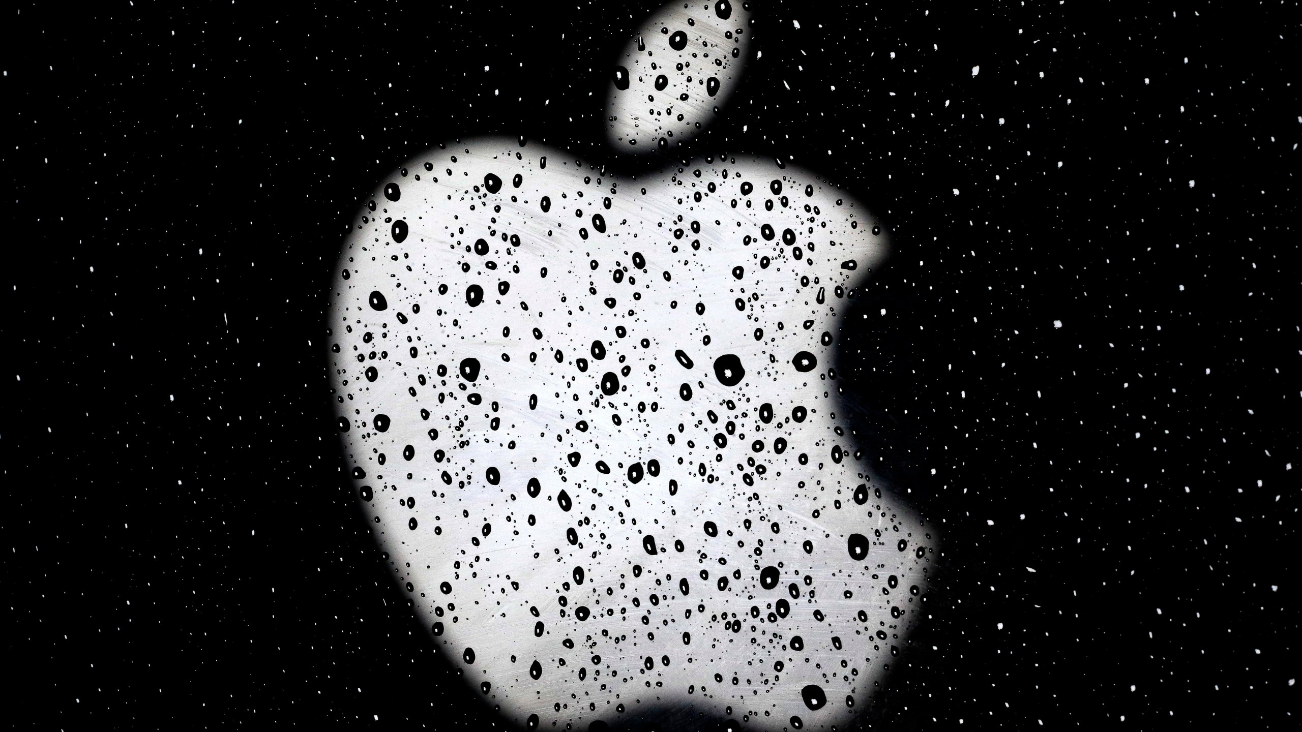 An Apple logo is seen in raindrops on a window outside an Apple Store at the Country Club Plaza shopping district in Kansas City, Mo., on Dec. 26, 2018. A former Apple employee has been charged with defrauding the tech giant out of more than $10 million by taking kickbacks, stealing equipment and laundering money. Federal prosecutors say they filed charges Friday, March 18, 2022, against Dhirendra Prasad. (AP Photo/Charlie Riedel, File)