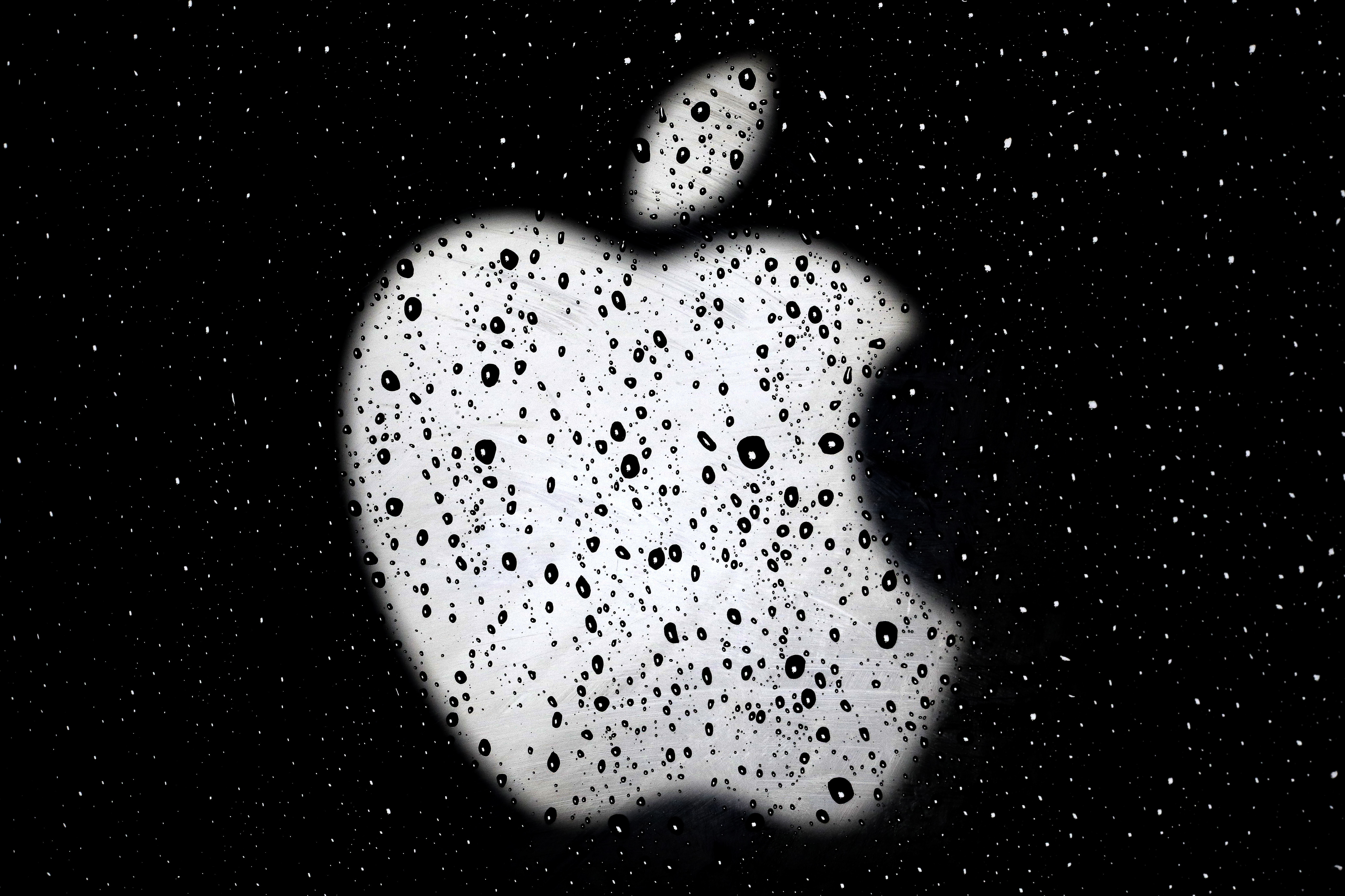 An Apple logo is seen in raindrops on a window outside an Apple Store at the Country Club Plaza shopping district in Kansas City, Mo., on Dec. 26, 2018. A former Apple employee has been charged with defrauding the tech giant out of more than $10 million by taking kickbacks, stealing equipment and laundering money. Federal prosecutors say they filed charges Friday, March 18, 2022, against Dhirendra Prasad. (AP Photo/Charlie Riedel, File)