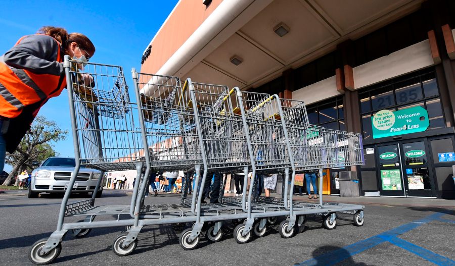 A Food 4 Less employee pushes carts past supermarket workers gathered to protest in front of the supermarket in Long Beach on Feb. 3, 2021. (FREDERIC J. BROWN/AFP via Getty Images)