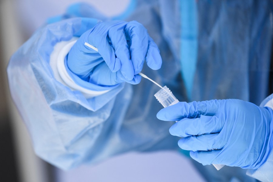 A health care worker places a test swab into solution for a PCR Covid-19 test at a testing site in Hawthorne, California on Jan. 18, 2022. (PATRICK T. FALLON/AFP via Getty Images)