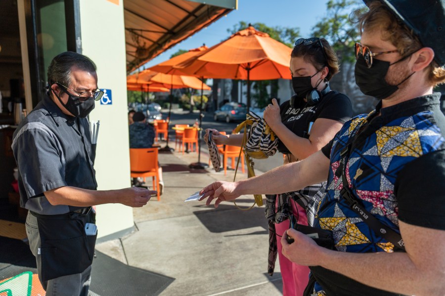 A waiter asks patrons to show their vaccination cards before entering the Fred 62 restaurant in Los Feliz on Nov. 29, 2021.(AP Photo/Damian Dovarganes, File)