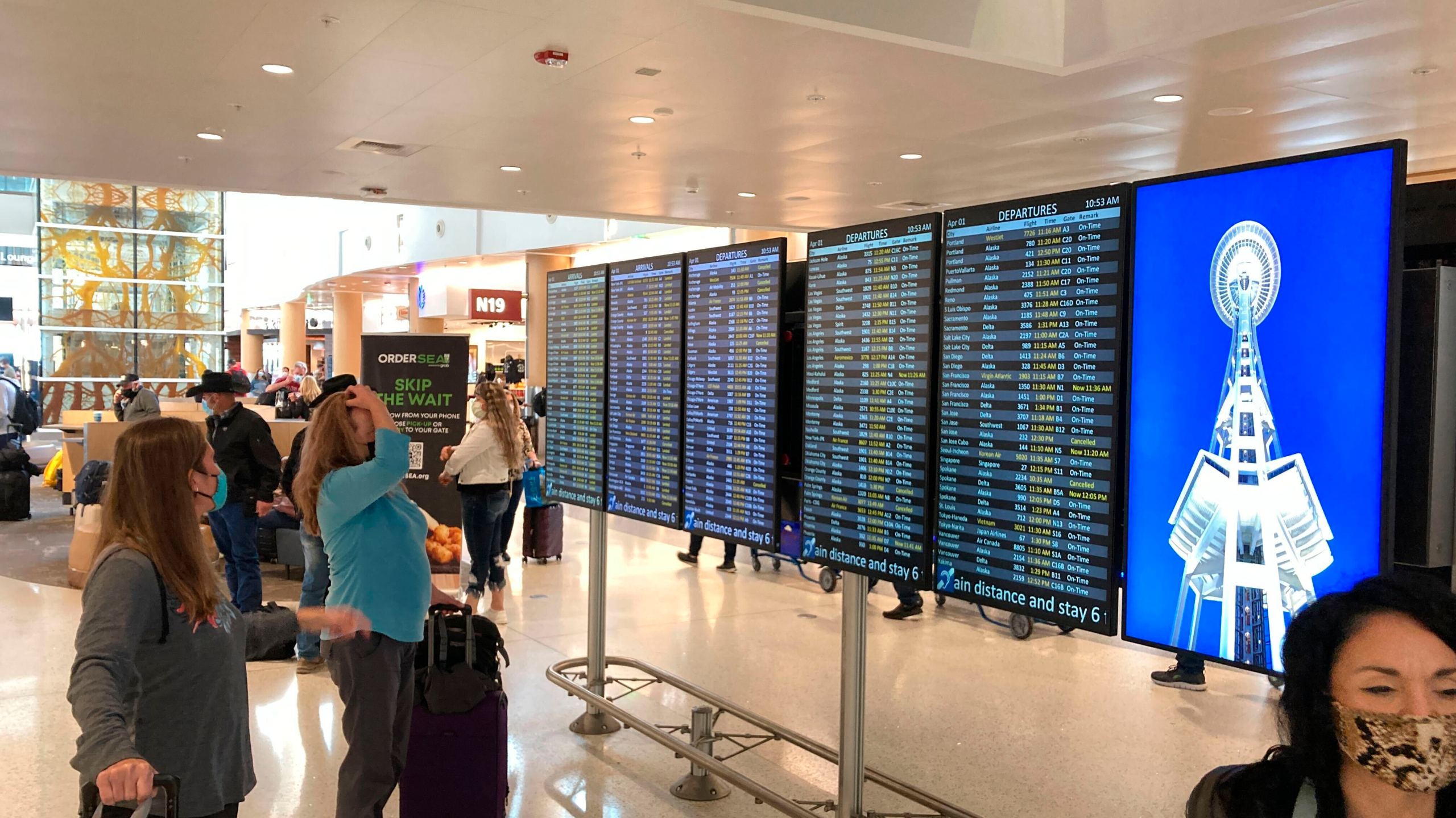 Travelers at Seattle-Tacoma International Airport check the status of flights, including a few that were canceled, on displays inside a gate terminal on April 1, 2022, in Seattle. (AP Photo/Ted S. Warren)