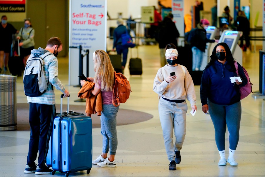 Travelers wearing protective masks as a precaution against the spread of the coronavirus move about the a terminal at the Philadelphia International Airport on April 19, 2022. (Matt Rourke/Associated Press)