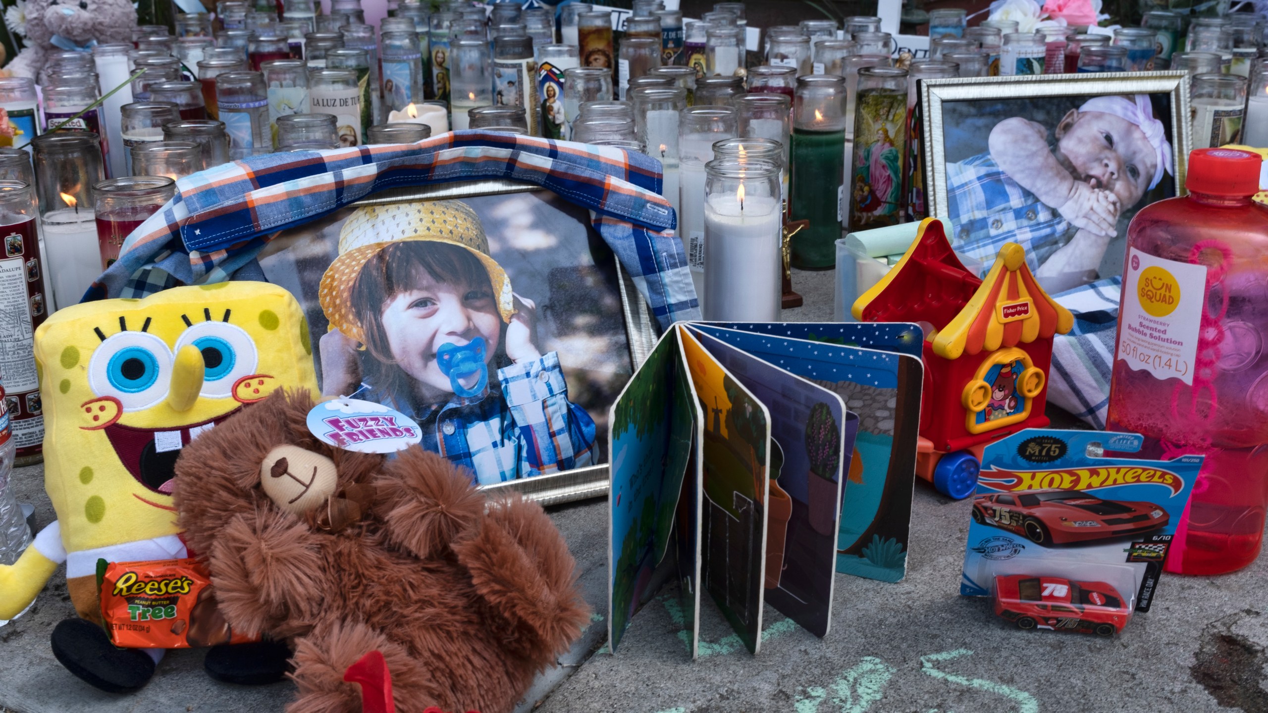 Photos, candles, flowers and balloons are placed as a memorial for three children who were killed at the Royal Villa apartments complex in the Reseda section of Los Angeles, April 12, 2021. Erik Denton, the father of the three children filed a lawsuit, Thursday, April 21, 2022, against the city and county of Los Angeles, accusing police and social workers of failing to intervene to protect his children before their deaths. (AP Photo/Richard Vogel, File)